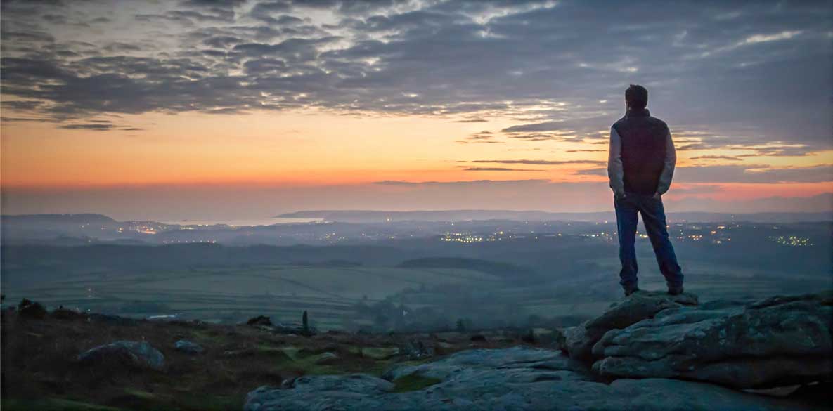 Man looking at sunset over horizon